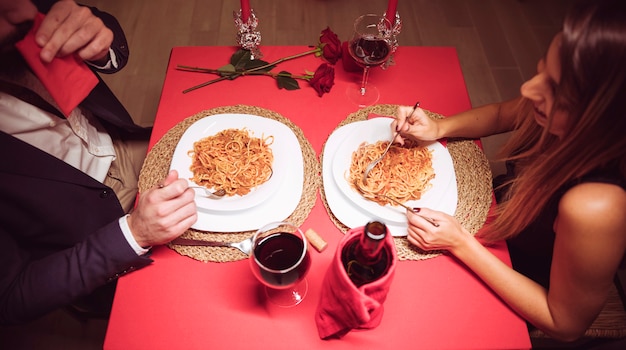 Giovani coppie che mangiano pasta al tavolo festivo