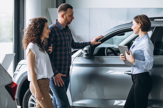 Giovani coppie che parlano con un venditore in una sala d'esposizione dell'automobile