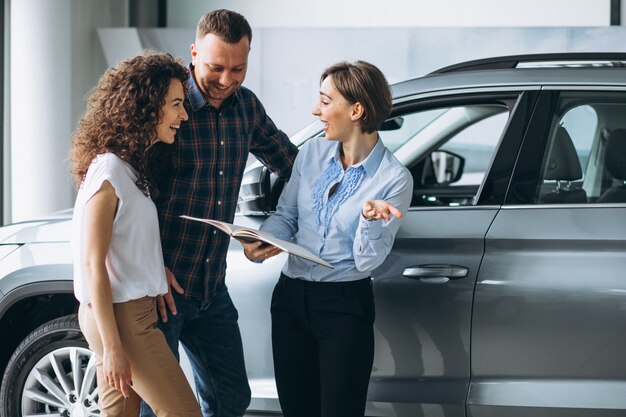 Giovani coppie che parlano con un venditore in una sala d'esposizione dell'automobile