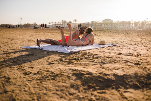 Giovani coppie che prendono il sole sulla spiaggia nelle vacanze estive