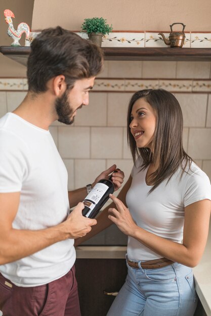 Giovani coppie che scelgono vino in cucina