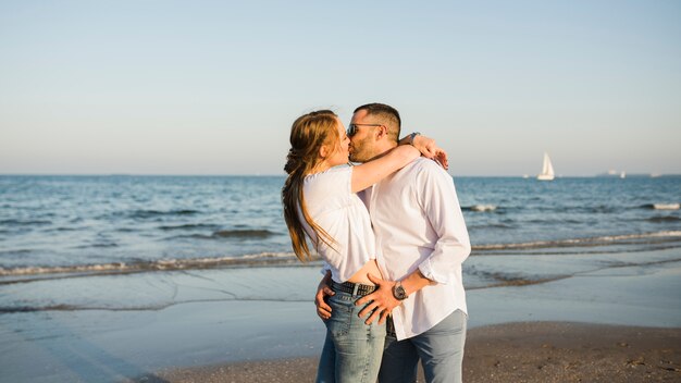 Giovani coppie che si baciano vicino al mare in spiaggia