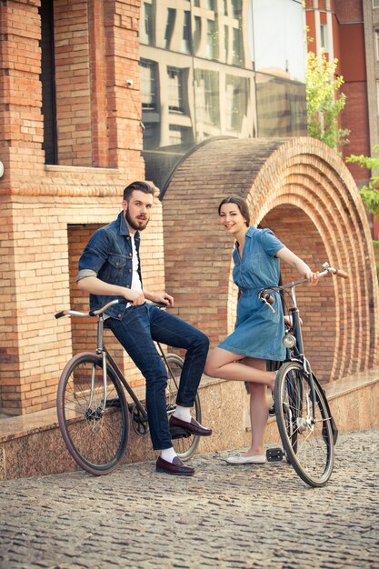 Giovani coppie che si siedono su una bicicletta di fronte alla città
