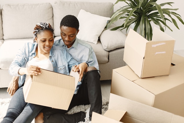 Giovani coppie che si trasferiscono insieme nella nuova casa. Coppia afro-americana con scatole di cartone.