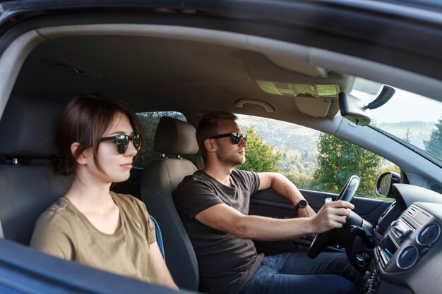 Giovani coppie che sorridono, sedendosi in automobile, godendo del Mountain View