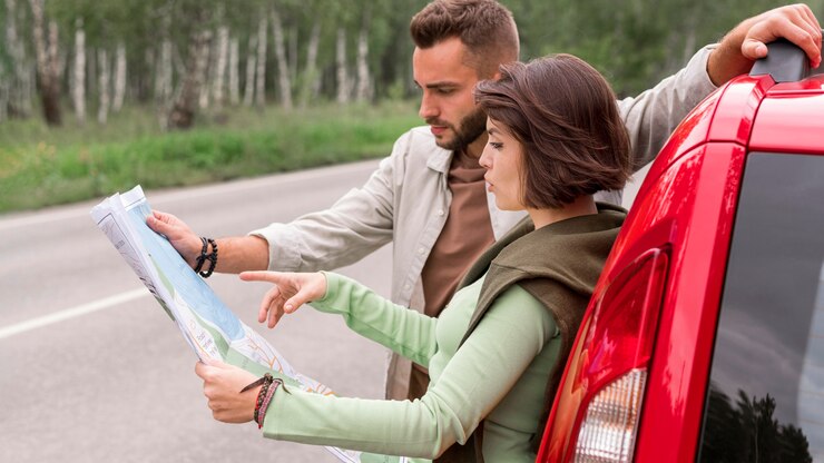 Foto gratuito giovani coppie che stanno vicino all'automobile che osserva sulla mappa