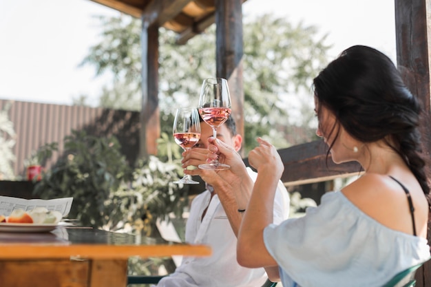 Giovani coppie che tostano i vetri di vino nel giardino