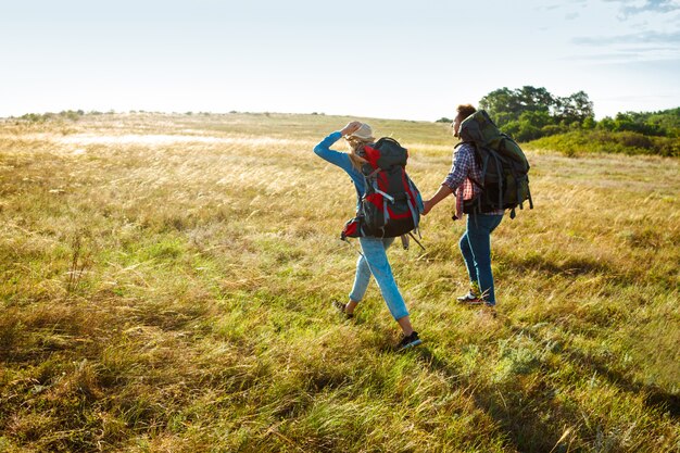 Giovani coppie di viaggiatori che camminano nel campo con il cane del carlino
