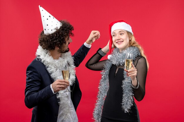 Giovani coppie di vista frontale che celebrano appena il nuovo anno su una festa rossa della parete amano il Natale