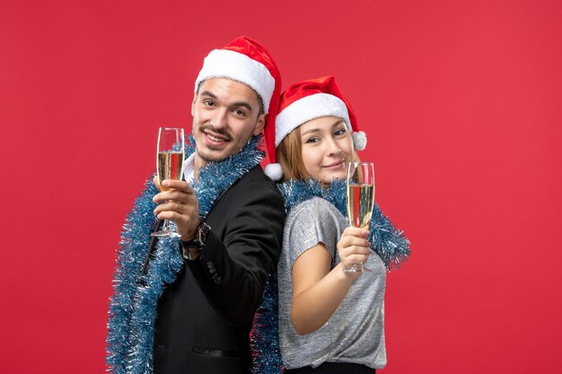 Giovani coppie di vista frontale che celebrano appena il nuovo anno su una festa rossa della parete amano il Natale