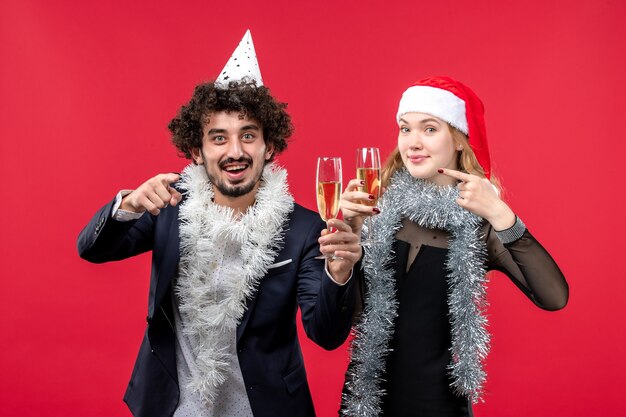 Giovani coppie di vista frontale che celebrano felicemente il nuovo anno sull'amore rosso di natale della foto della parete