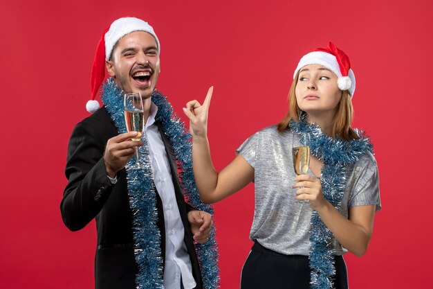 Giovani coppie di vista frontale che celebrano il nuovo anno sul colore rosso di natale di amore del pavimento