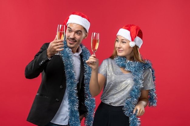 Giovani coppie di vista frontale che celebrano il nuovo anno sul natale rosso di amore di colore del pavimento