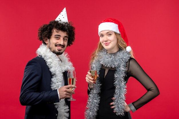 Giovani coppie di vista frontale che celebrano il nuovo anno sull'amore di natale di festa della parete rossa