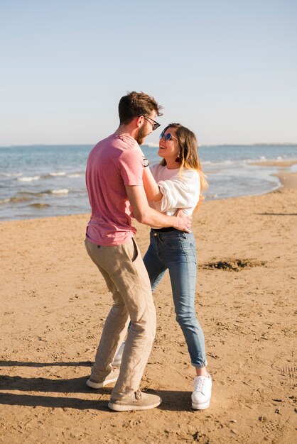 Giovani coppie felici divertendosi alla spiaggia il giorno soleggiato