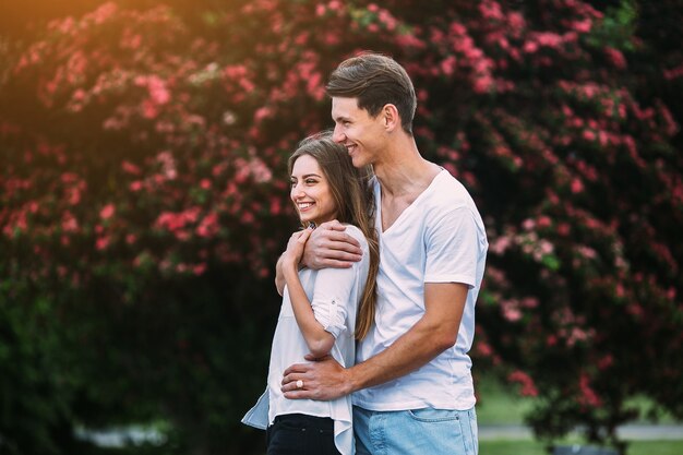 Giovani coppie felici nell'amore all'aperto. amorevole uomo e donna durante una passeggiata in un parco in fiore primaverile