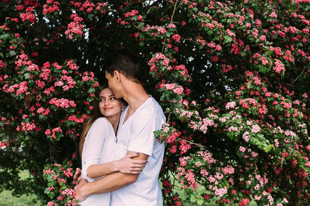 Giovani coppie felici nell'amore all'aperto. amorevole uomo e donna in una passeggiata in un parco fiorito primaverile