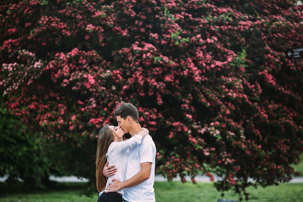 Giovani coppie felici nell'amore all'aperto. amorevole uomo e donna in una passeggiata in un parco fiorito primaverile