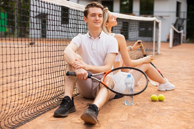 Giovani coppie insieme al campo da tennis