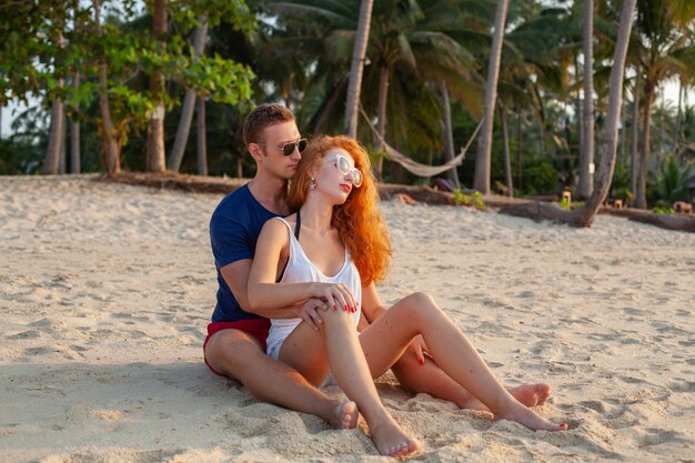 Giovani coppie nell'amore felice sulla spiaggia di estate insieme divertendosi