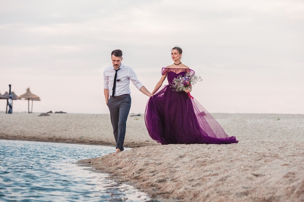 Giovani coppie romantiche che funzionano sulla spiaggia del mare