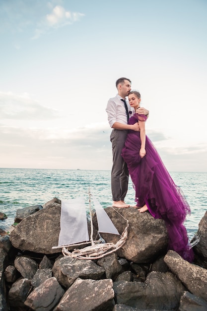 Giovani coppie romantiche che si rilassano sulla spiaggia che guarda il tramonto