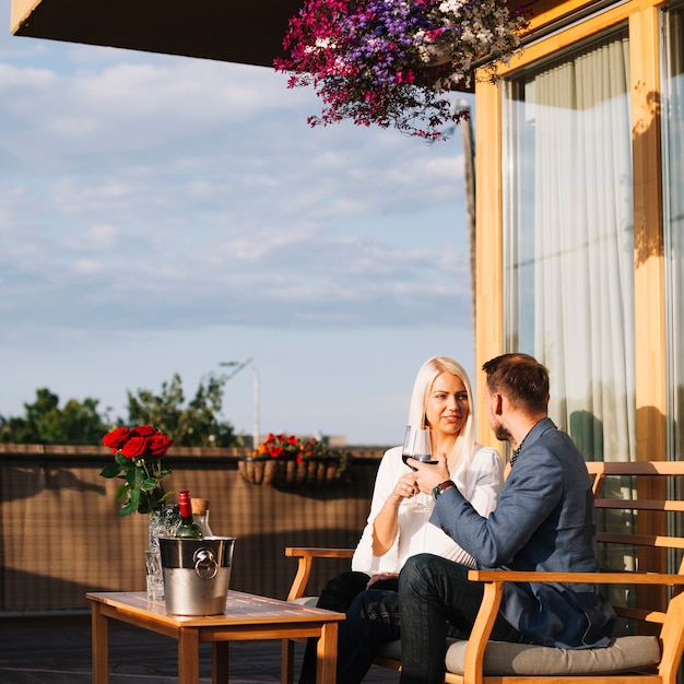 Giovani coppie romantiche che si siedono nel ristorante del tetto che gode della bevanda