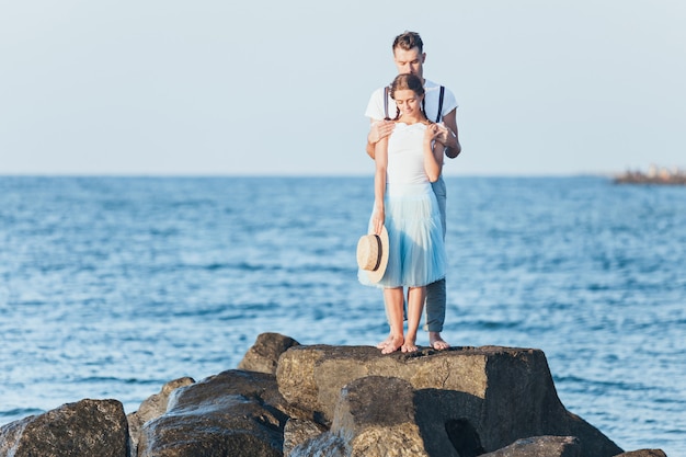 Giovani coppie romantiche felici che si rilassano sulla spiaggia e che guardano il tramonto