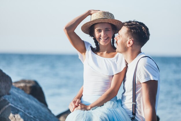 Giovani coppie romantiche felici che si rilassano sulla spiaggia e che guardano il tramonto