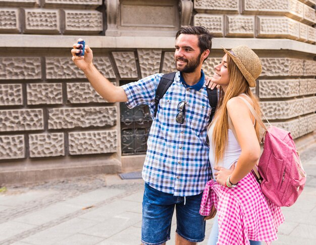 Giovani coppie sorridenti che prendono selfie sul telefono cellulare