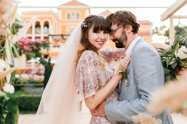 Giovani coppie, sposa e sposo che posano vicino alla villa di lusso. Decorazioni per matrimoni. Momenti romantici.