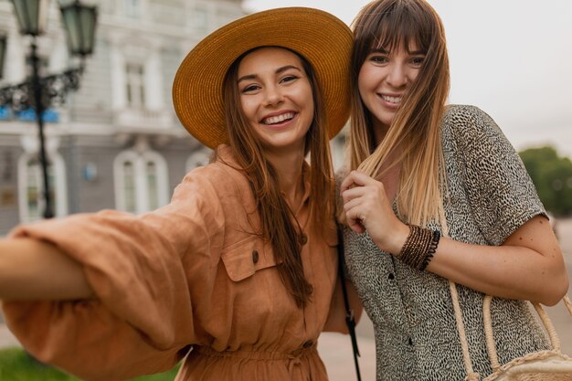 Giovani donne alla moda che viaggiano insieme in Europa vestite con abiti e accessori alla moda primaverili