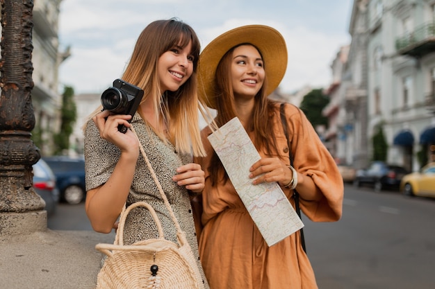 Giovani donne alla moda che viaggiano insieme in Europa vestite con abiti e accessori alla moda primaverili