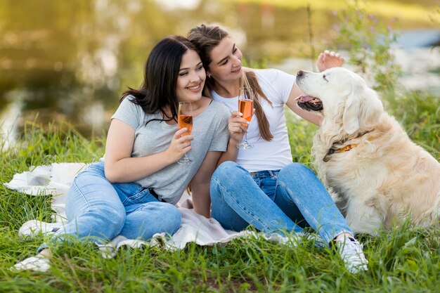 Giovani donne che bevono accanto a un cane all'aperto