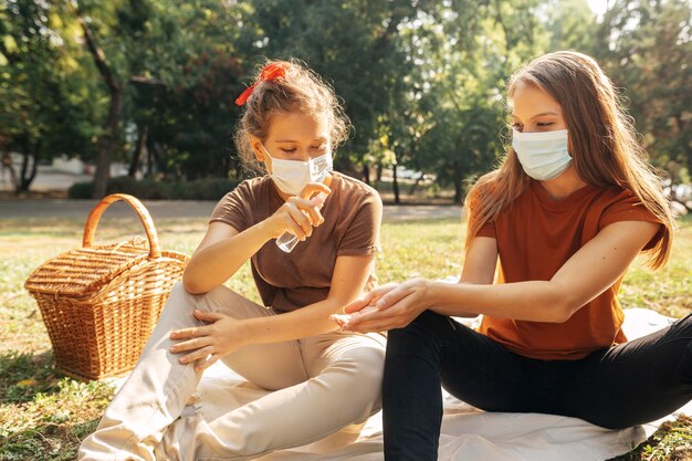 Giovani donne che disinfettano prima di fare un picnic