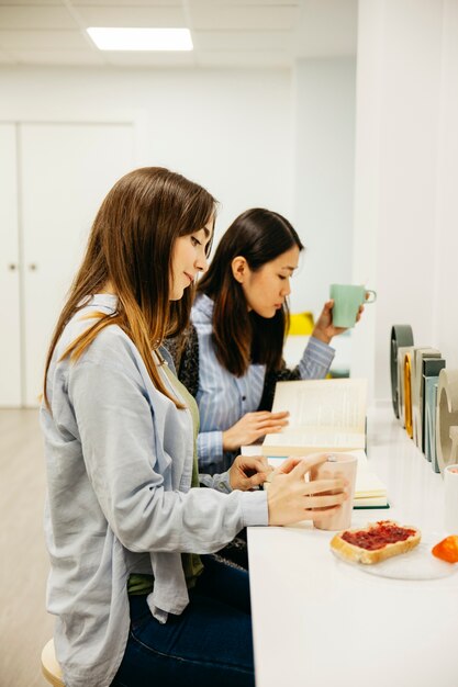 Giovani donne che godono colazione e lettura