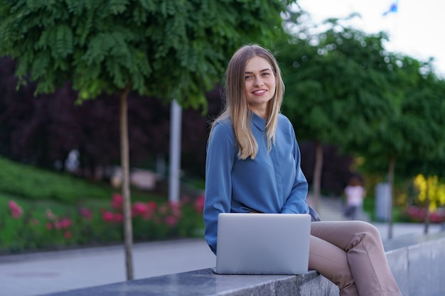 Giovani donne che lavorano al computer portatile nella piazza della città