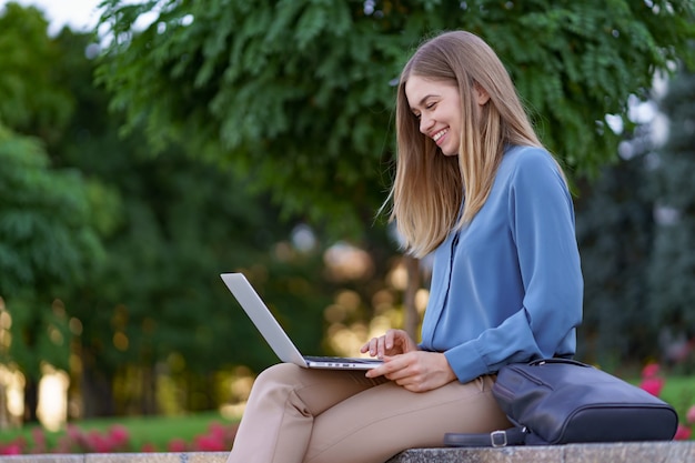 Giovani donne che lavorano al computer portatile nella piazza della città