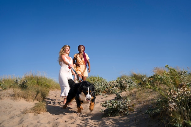 Giovani donne che si divertono con il cane in spiaggia