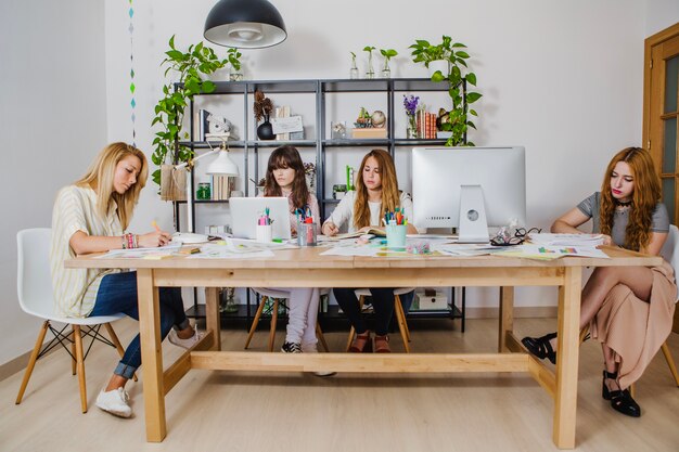 Giovani donne che si riuniscono al tavolo creando