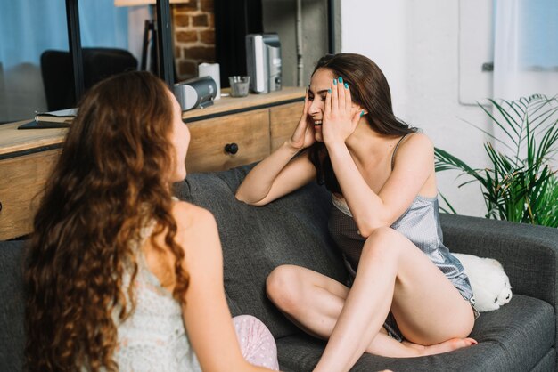 Giovani donne che si siedono sul divano a casa