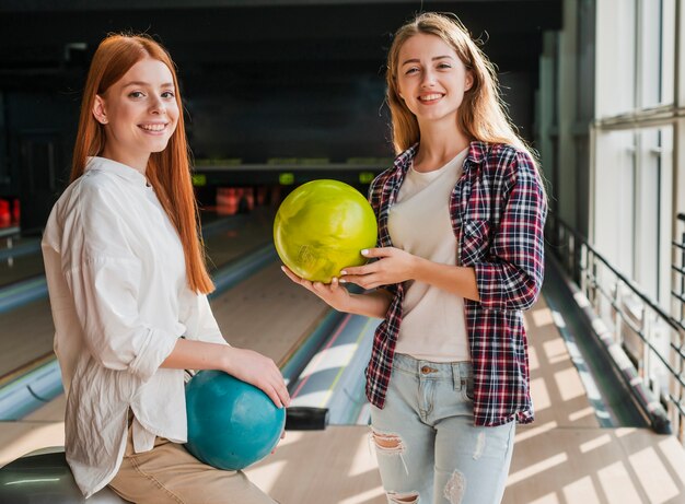 Giovani donne che tengono le palle da bowling variopinte