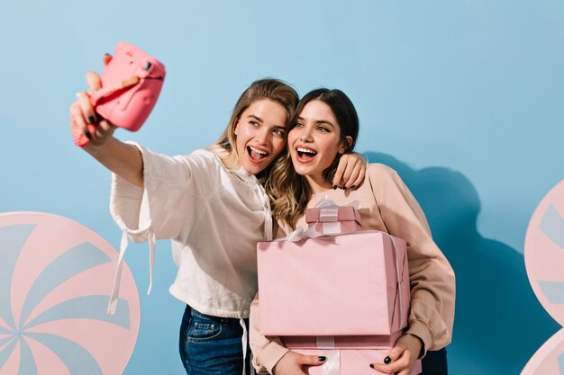 Giovani donne con fotocamera rosa prendendo selfie