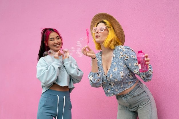 Giovani donne con i capelli tinti vicino al muro rosa