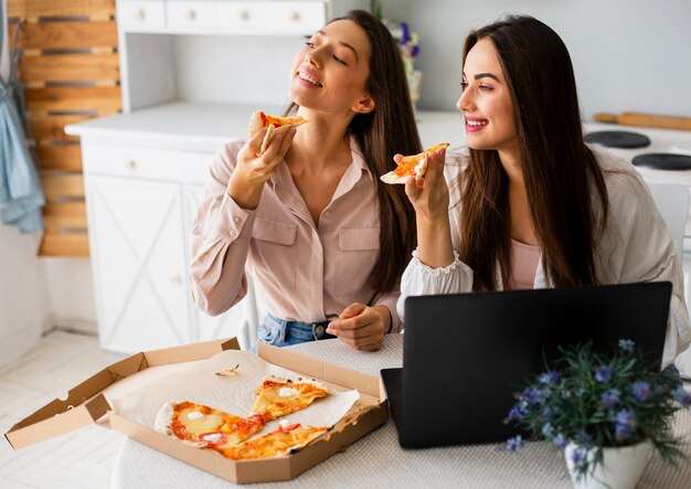 Giovani donne dell'angolo alto che mangiano pizza
