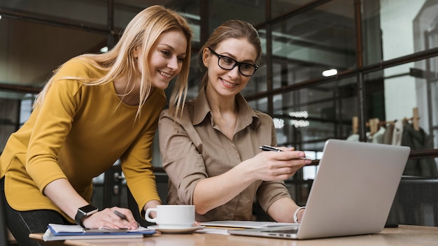 Giovani donne di affari di smiley che lavorano con il computer portatile allo scrittorio