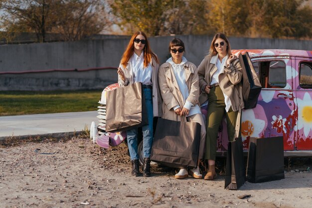 Giovani donne in posa vicino a una vecchia automobile decorata