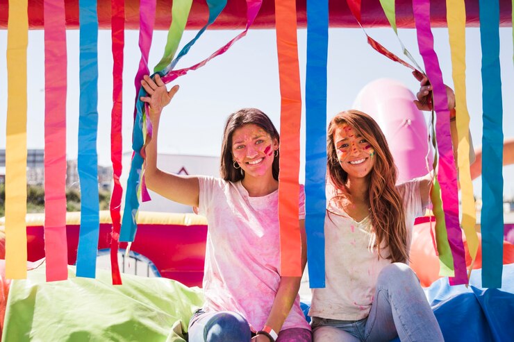 Foto gratuito giovani donne sorridenti con il colore di holi sul loro volto che guarda l&#39;obbiettivo