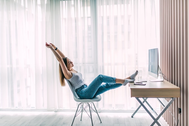 Giovani femmine libero professionista stretching e relax lavorando sul computer portatile in ufficio a casa