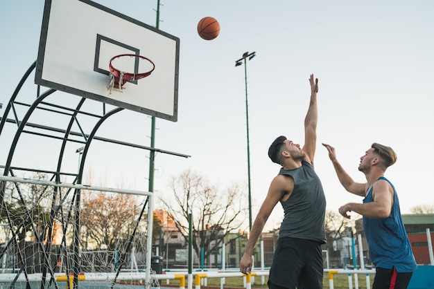 Giovani giocatori di basket che giocano uno contro uno sul campo all'aperto. Concetto di sport e basket.